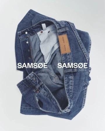 Folded blue denim jeans by Samsøe Samsøe on a white backdrop, showcasing the brand's label and design details in a studio product shot.