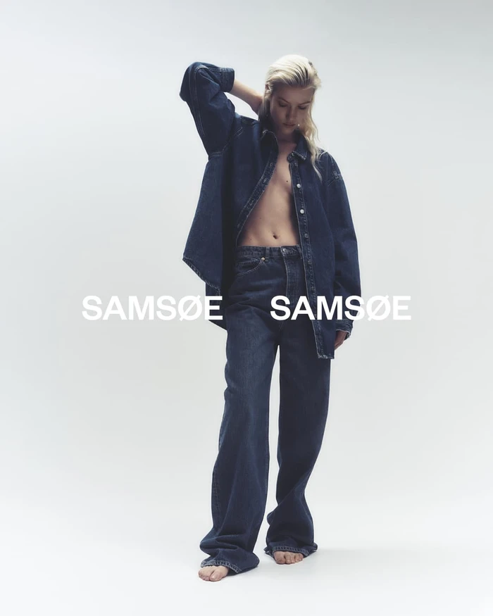 Model standing in denim shirt and jeans against white backdrop for Samsoe Samsoe Spring 2024 ad campaign