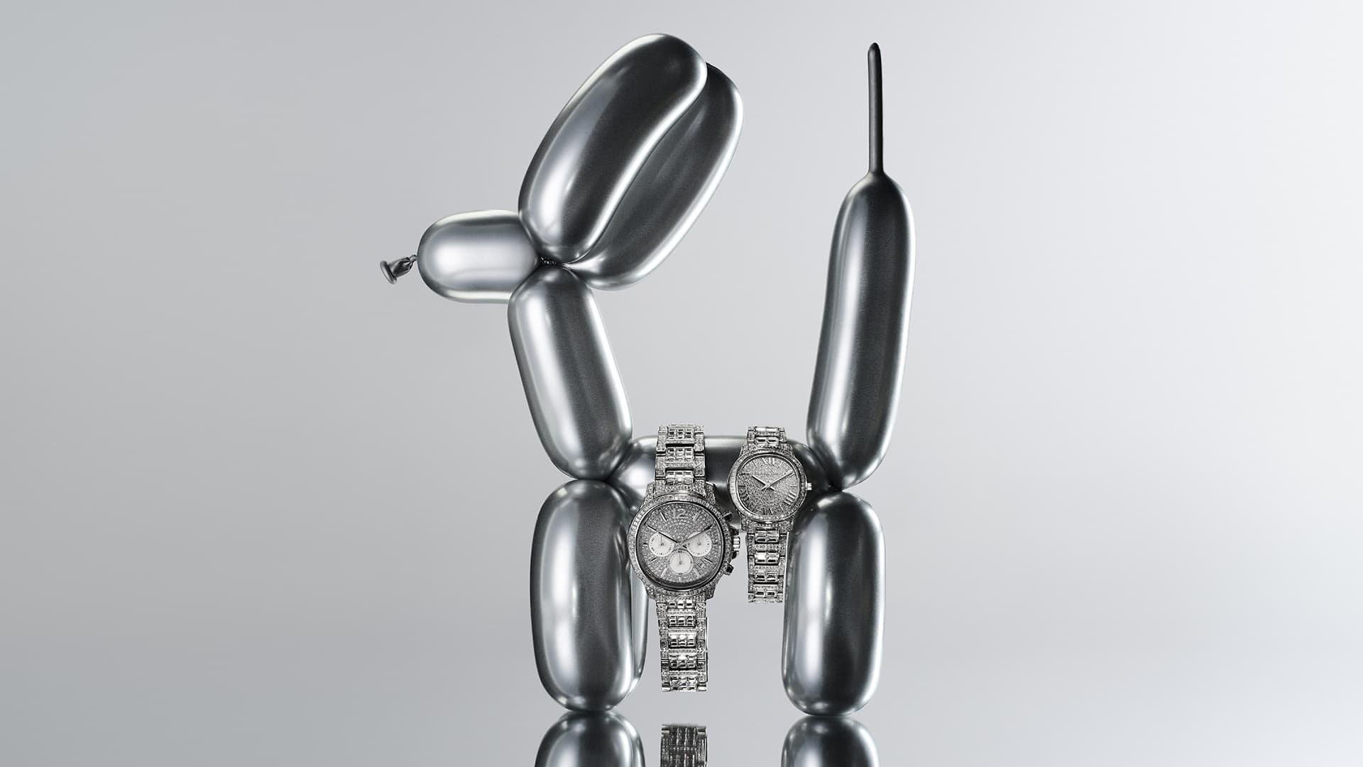 Two silver wristwatches positioned on a reflective surface in front of a balloon dog sculpture on a gray gradient background.