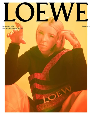 Magazine cover featuring a fair-skinned adult woman in a Loewe sweater, gazing into the camera. She is wearing light makeup, and has tattoos.