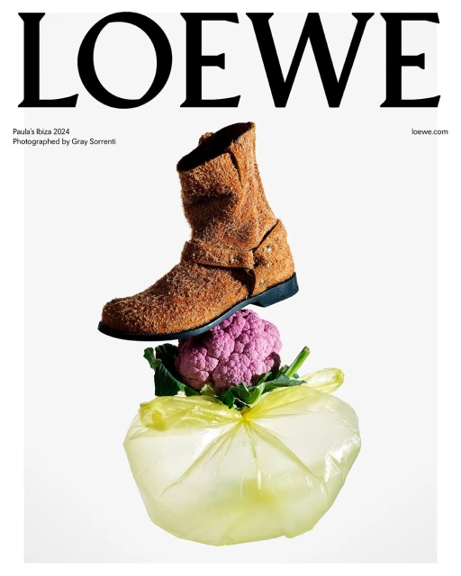 Loewe editorial fashion shot featuring a brown boot balanced on top of a purple cauliflower and plastic bag on a white backdrop.