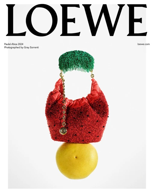 Loewe editorial fashion still life: red beaded handbag on top of yellow citrus fruit, adorned with green beaded fringe accessory.