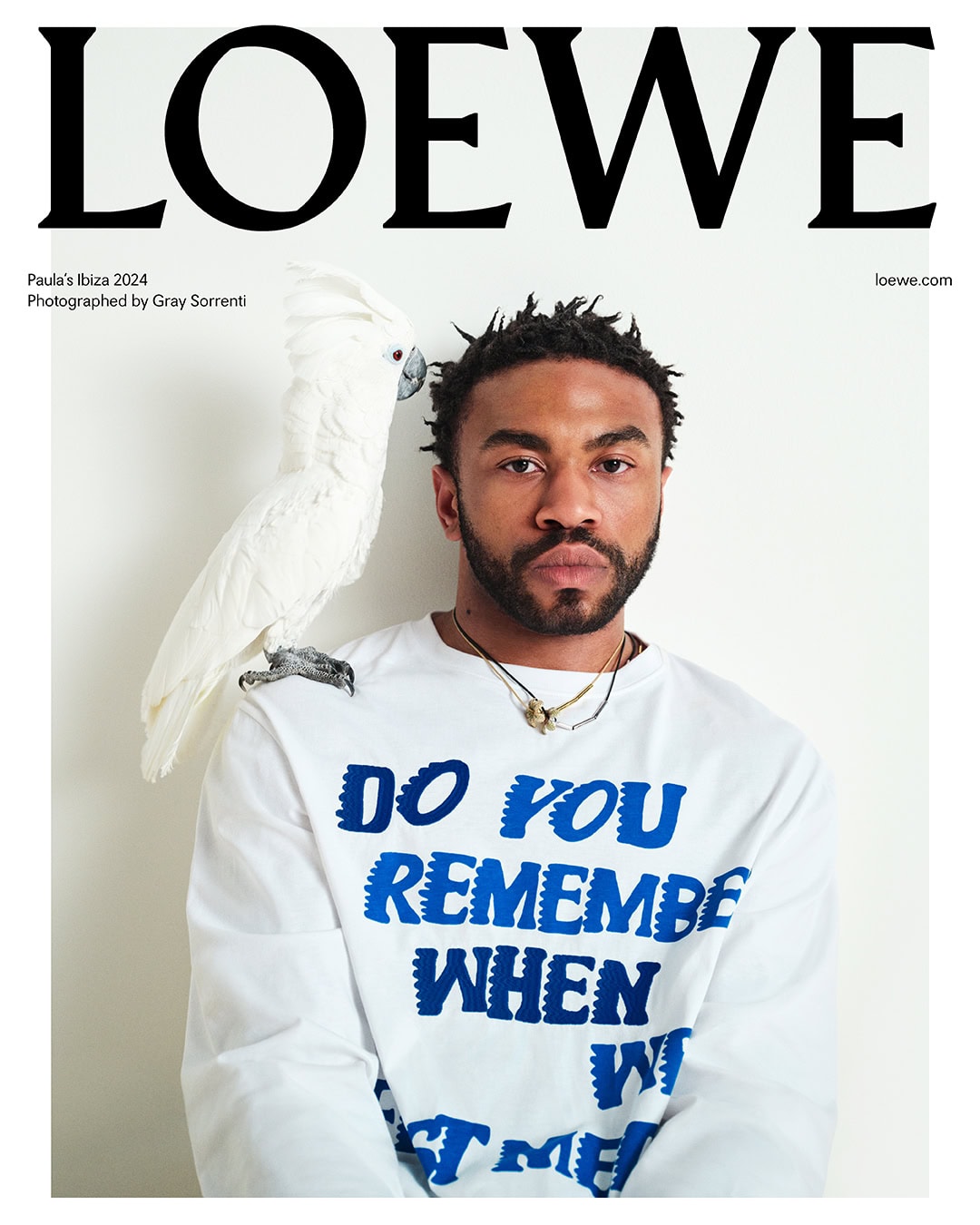 Fashion magazine cover featuring a black male model in a Loewe shirt with a white parrot perched on his shoulder, against a plain background.