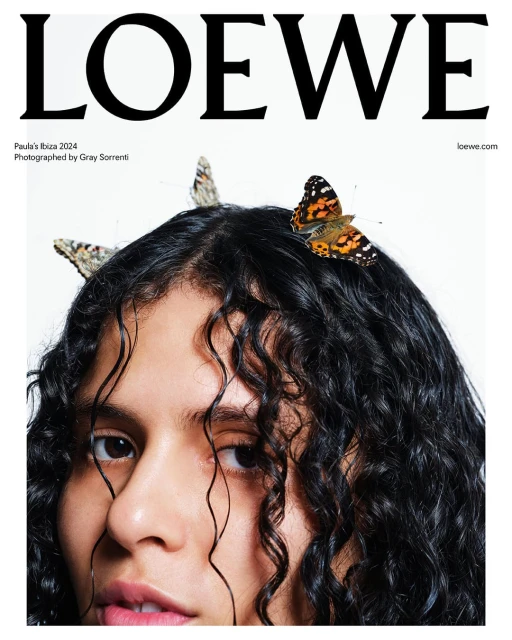 Fashion editorial image featuring a young woman with curly hair adorned with butterflies, promoting LOEWE Paula's Ibiza 2024 collection.
