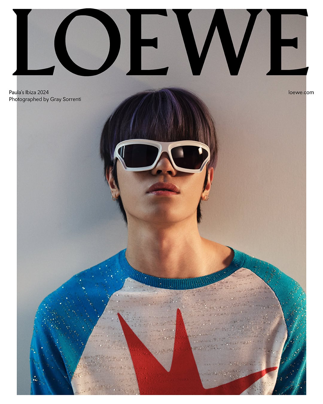 Magazine cover featuring a model wearing sunglasses and a star patterned top against a neutral backdrop, showcasing a Loewe advertisement.