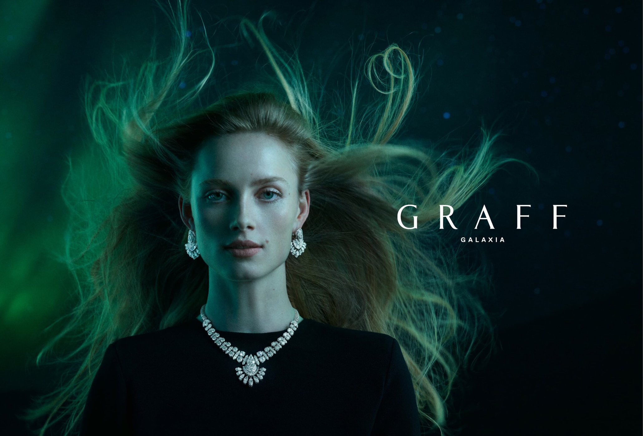 Fashion advertisement featuring a woman with flowing hair wearing a Graff diamond necklace and earrings against a green and black backdrop.