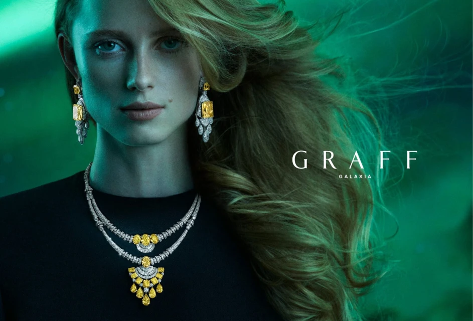 Woman wearing Graff Galaxia jewelry: yellow diamond earrings and necklace against a green and blue background with text overlay.