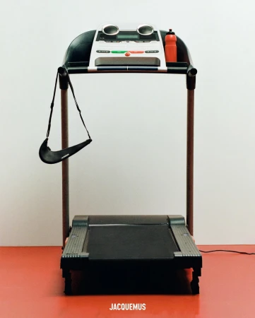 Treadmill with Nike purse, a Jacquemus collaboration, in a minimalist setting with a white wall and red floor.  Minimalist, modern.