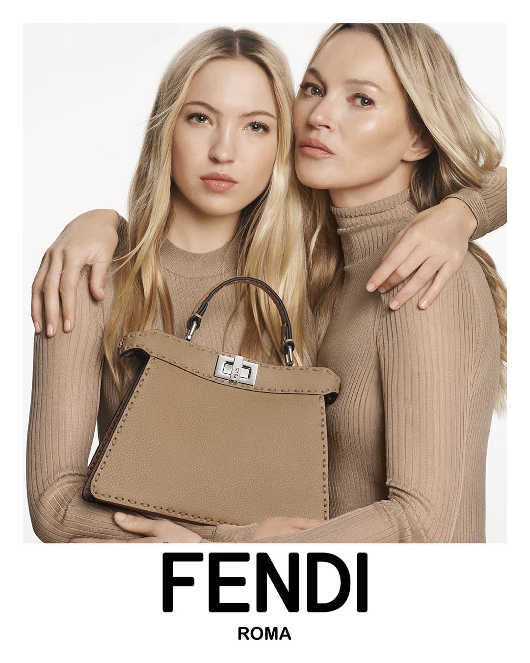 Lila Moss and Kate Moss wearing beige ribbed turtleneck tops holding a Fendi Peekaboo handbag against a neutral white background