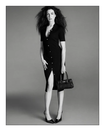 Black and white fashion shot of an adult woman in a black collared dress with a purse and high heels, posing in a studio.