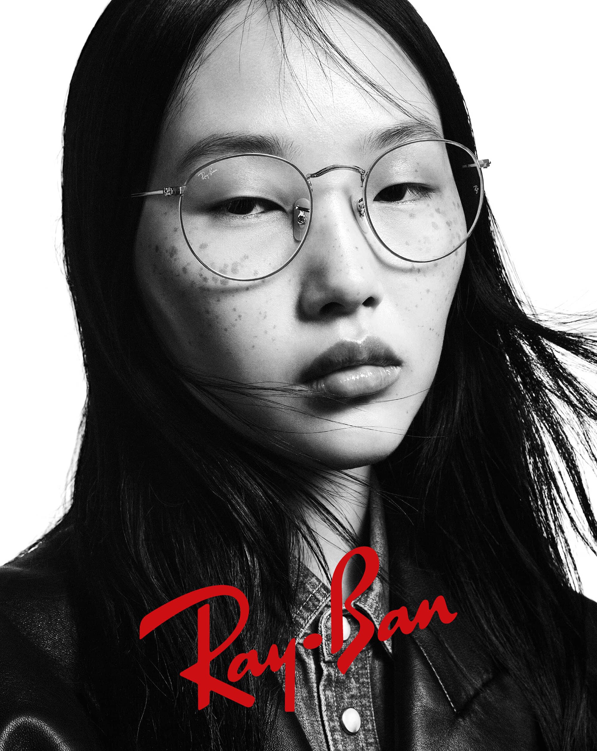 Headshot of an Asian woman with dark hair wearing glasses and a denim shirt with a black jacket, featuring a red Ray-Ban logo.