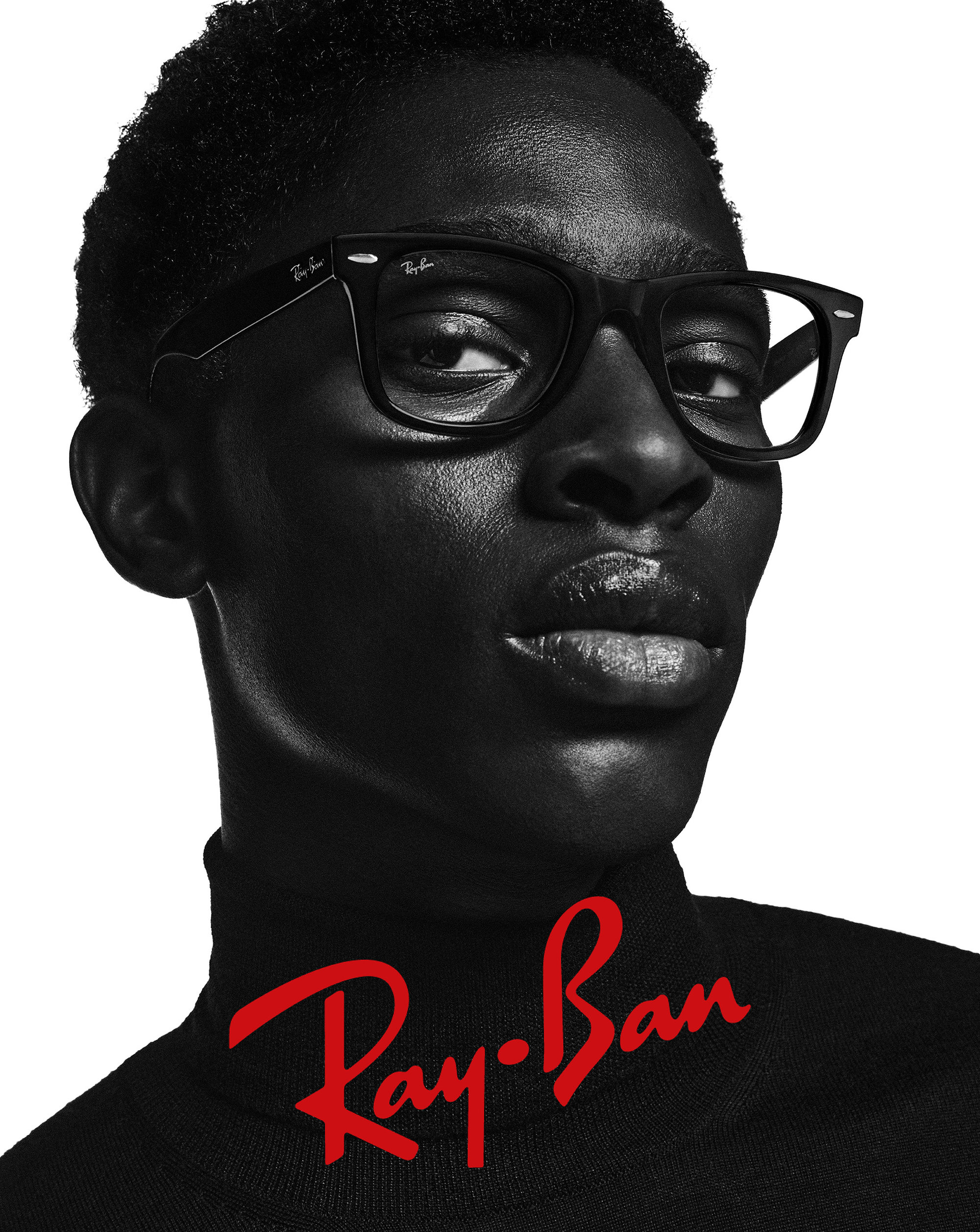 Close-up studio shot of a Black male model wearing Ray-Ban eyeglasses and a black turtleneck, showcasing Ray-Ban branding and eyewear.