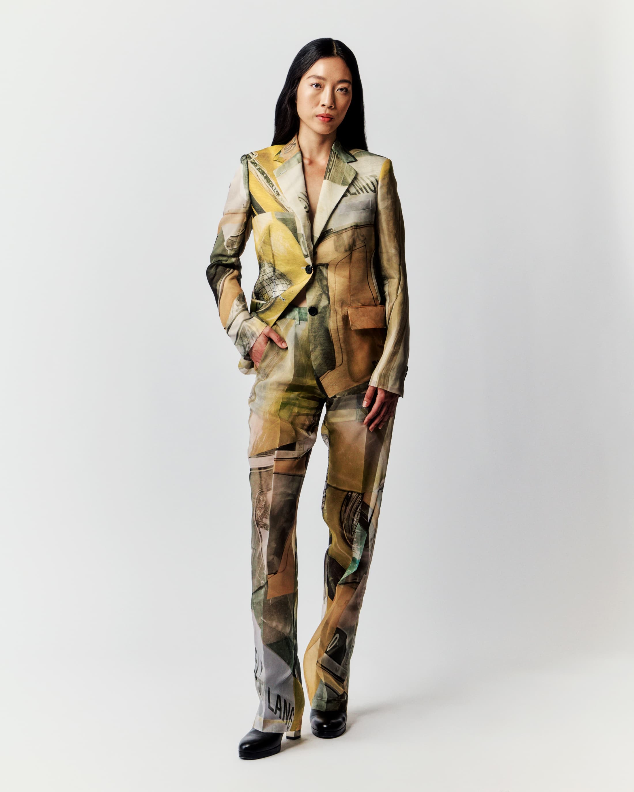 Asian woman posing in a fashionable printed blazer and pants suit against a clean white background in a full-length studio shot.
