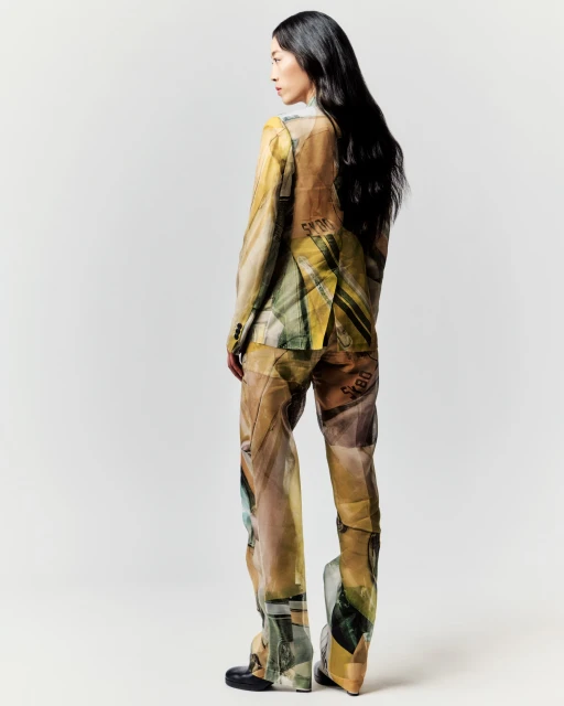 Back view of an Asian fashion model wearing a printed pantsuit in a studio setting with black footwear and long, dark hair.