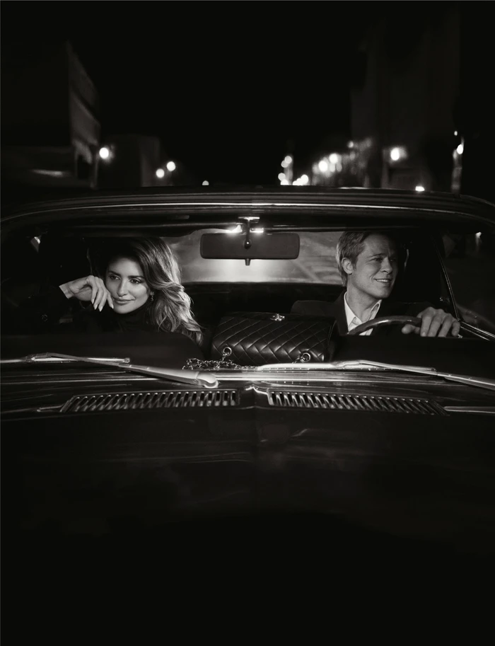 Penelope Cruz and Brad Pitt seated together inside a classic car at night for a Chanel ad campaign.