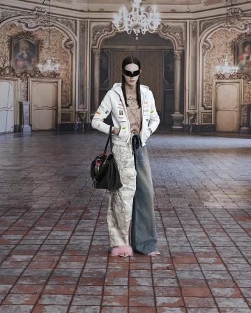A person stands in a grand, ornate room wearing an eclectic outfit including a white hoodie, mismatched jeans, and pink fuzzy slippers.