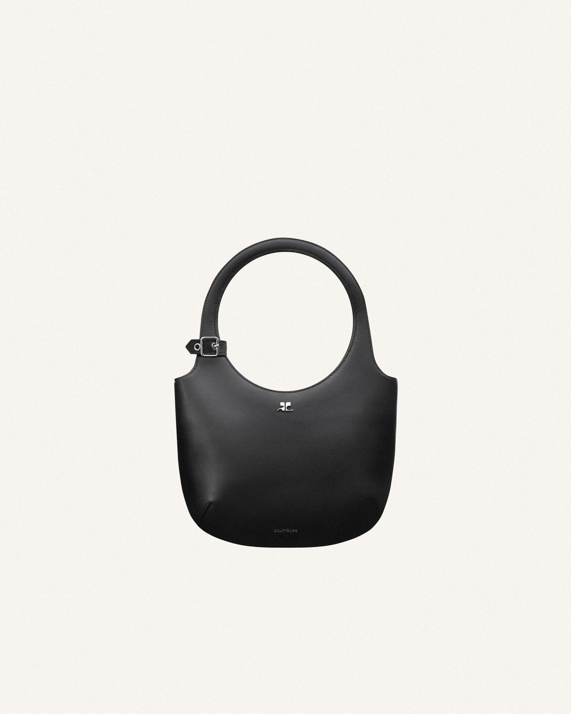 Studio shot of a black leather hobo bag with round handle and silver hardware, presented on an off-white backdrop.