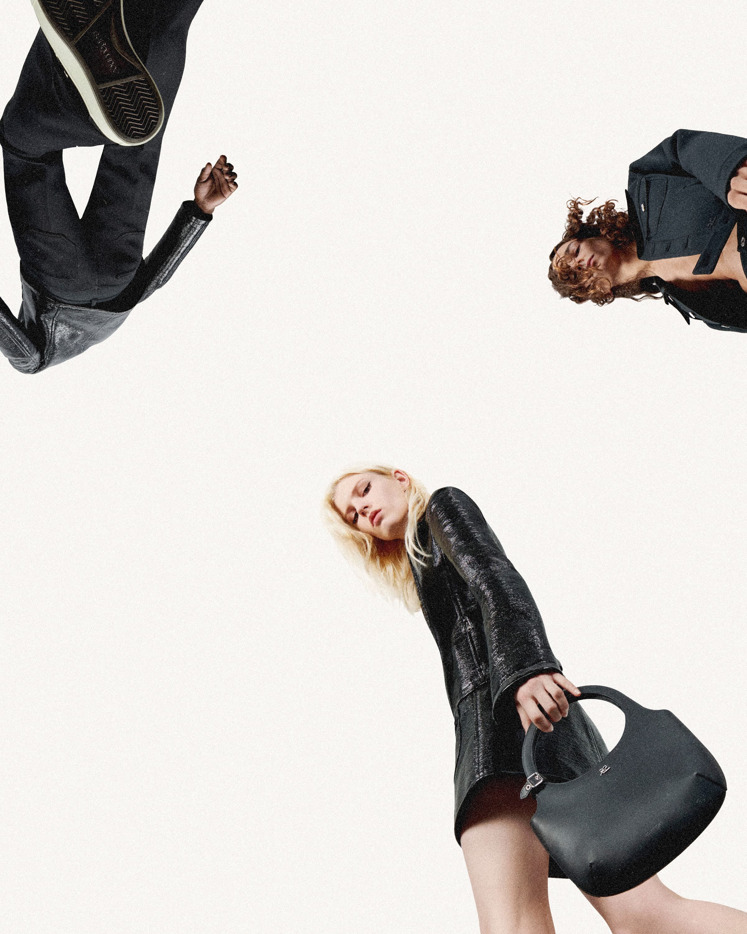 Fashion editorial shot from low angle with three adult models wearing dark jackets and dresses against a clean white background.
