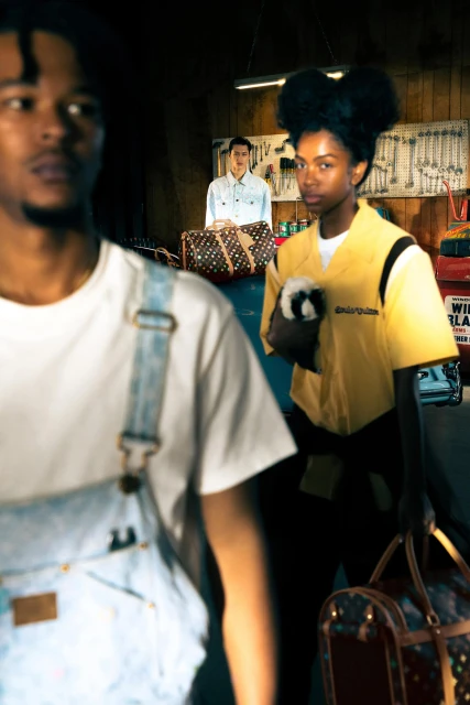 Fashion editorial photo in a garage setting featuring two African American adults and one Caucasian adult, all with luggage.