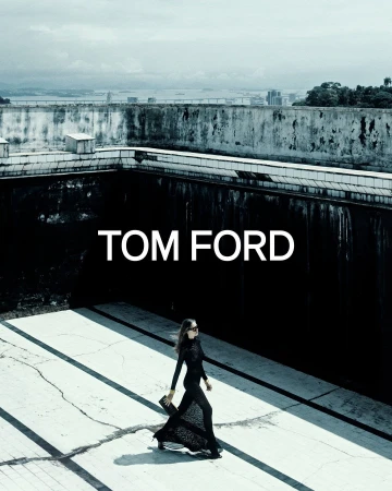 Model in black clothing walking across a concrete rooftop with urban background for Tom Ford