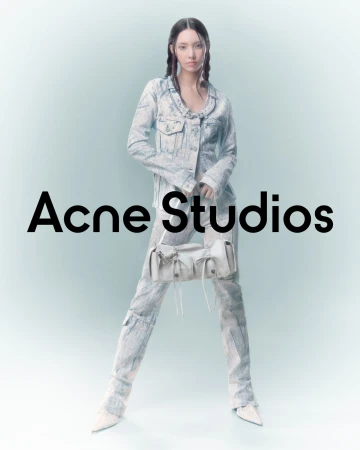 A woman poses in a light-blue tie-dye denim jacket and pants, holding a light-colored bag with black Acne Studios text overlayed.
