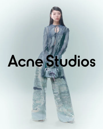 Asian woman in an open-front, light blue and white printed ensemble holding a matching purse against a bright background.