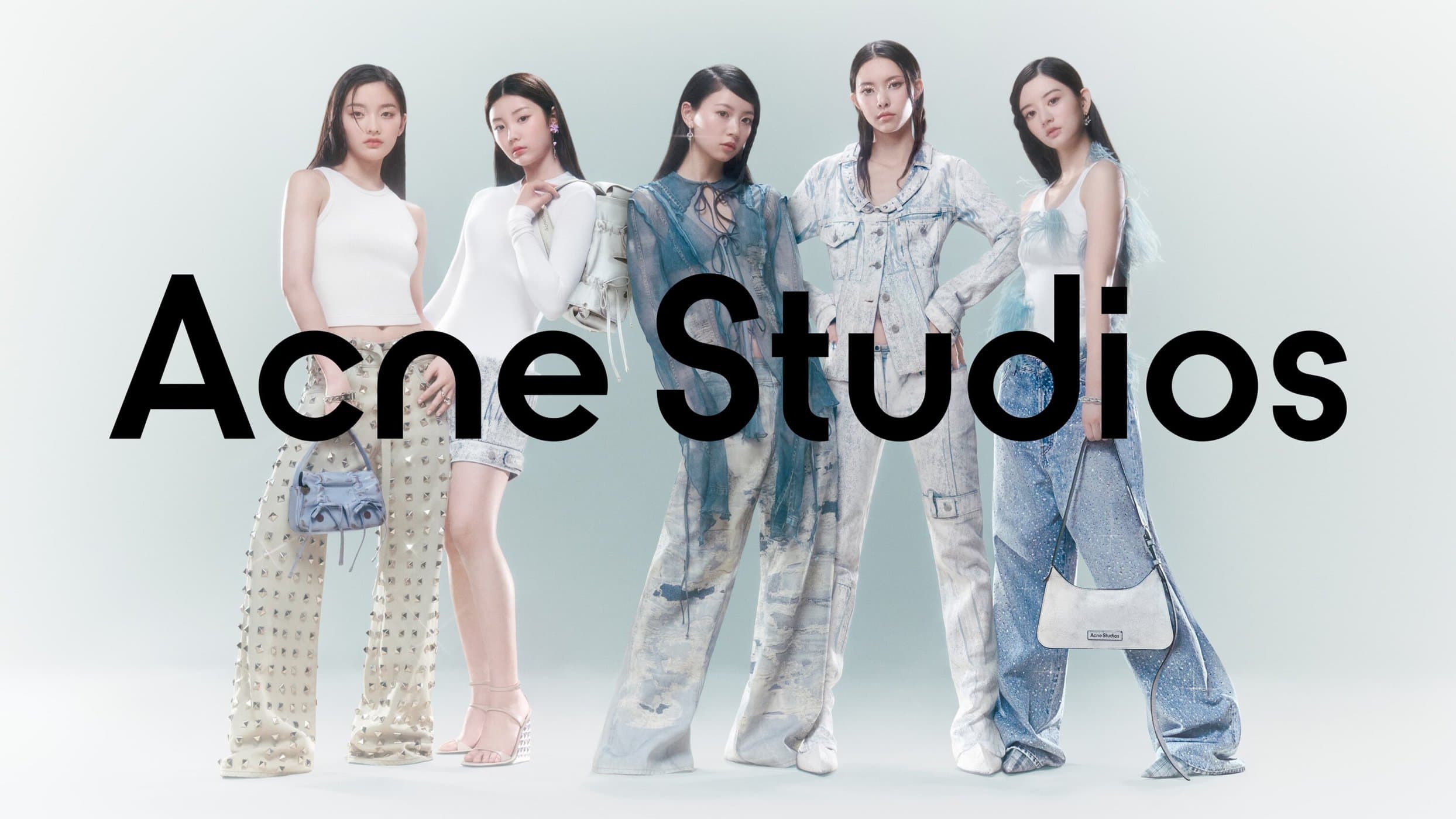 Five Asian fashion models pose in Acne Studios apparel, showcasing various outfits and accessories against a pale gradient background.