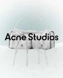 White leather shoulder bag with front pockets and dangling drawstrings resting on a white soft surface against a pale blue gradient background