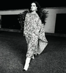 Model in patterned coat and white boots walking on lawn outdoors at night for Chanel Spring 2024 campaign