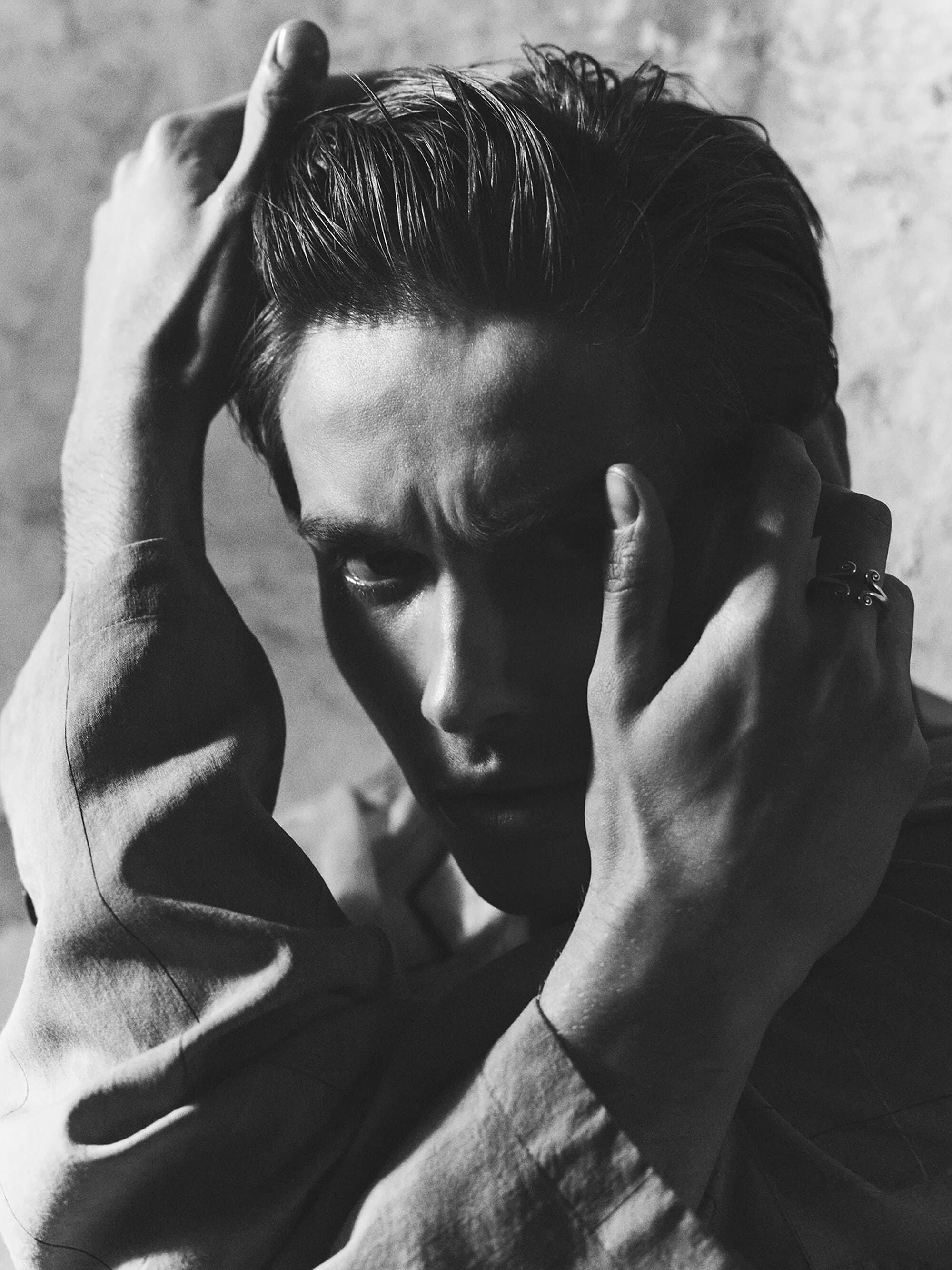 Close-up portrait of Toon Lobach wearing Zara apparel with hands framing face against a textured background