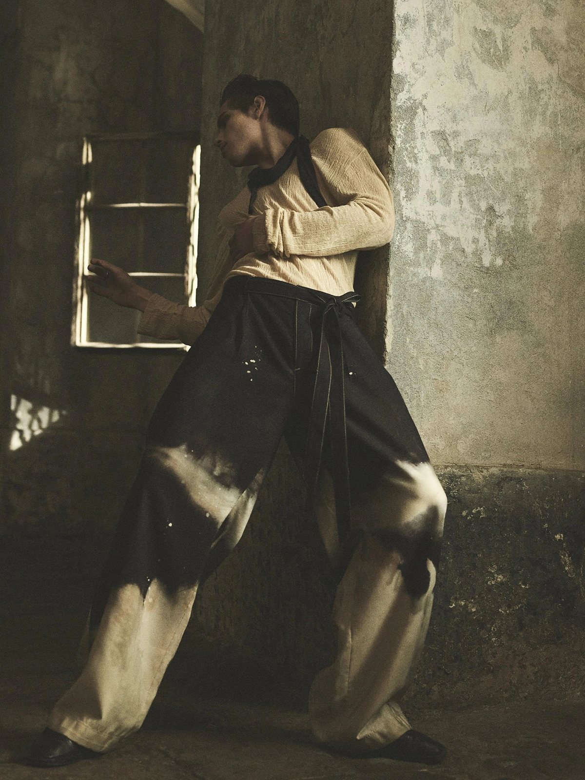 Model Toon Lobach leaning against a weathered stone pillar in a textured interior for the Zara Spring 2024 campaign