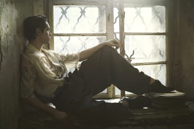 Model Toon Lobach seated on a windowsill against an old window for Zara Spring 2024 Men's Ad Campaign, photographed by Annemarieke van Drimmelen.
