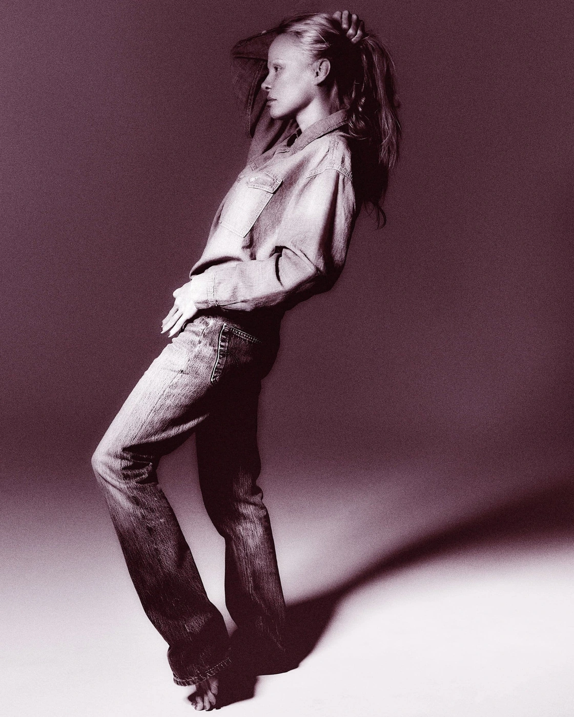 Model in denim shirt and jeans posing against a grey gradient studio background for RE/DONE