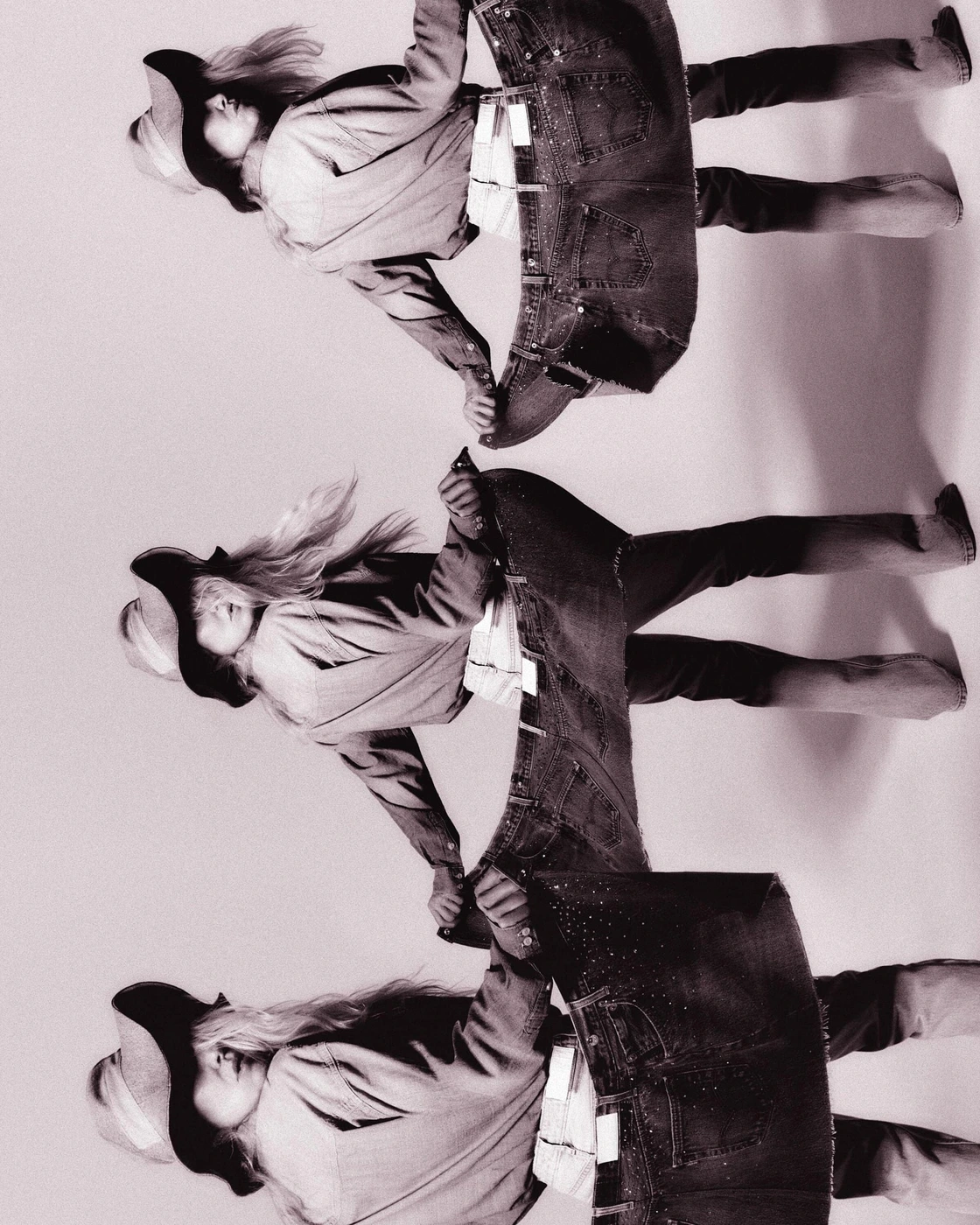 Monochrome multiple exposure image of a woman holding oversized denim jeans against a plain backdrop for RE/DONE.