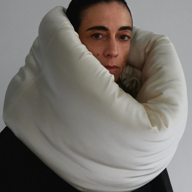 Close-up studio shot of a woman wearing a puffy white collar, emphasizing her facial expression and the collar's texture.