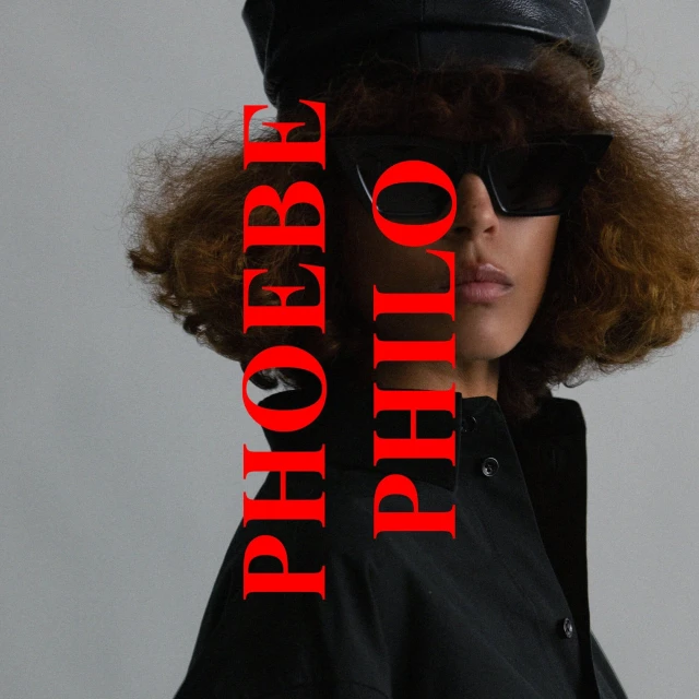 A person wearing black sunglasses and a black leather cap poses against a grey backdrop with red text overlaying the image.