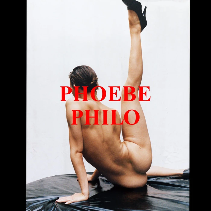 Model posing on a dark glossy surface with one leg raised high against a plain white backdrop