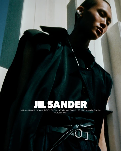 Fashion image showcasing a model in a dark outfit against a minimalist white background, promoting JIL SANDER's Spring/Summer 2024 collection.