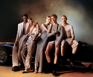Group of six models posing together against a vintage car in a studio setting for Ami Paris Spring 2024 campaign