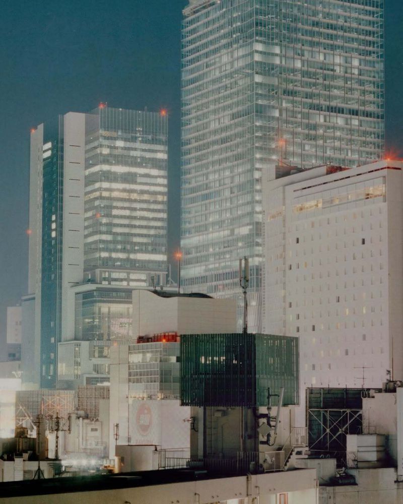 Night cityscape featuring illuminated skyscrapers with a cool color palette, creating a modern urban scene with dominant geometric shapes.