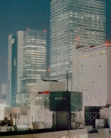 Night cityscape featuring illuminated skyscrapers with a cool color palette, creating a modern urban scene with dominant geometric shapes.