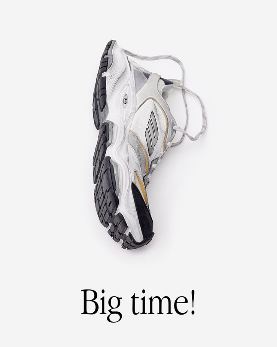 Fashionable athletic shoe on a white backdrop. Gray and white sneaker with black sole and laces. "Big time!" text overlay.