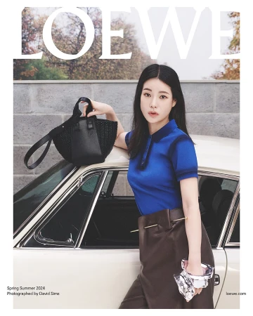 Fashion magazine cover featuring a young woman in a blue polo shirt and brown skirt next to a vintage car, holding a black bag.