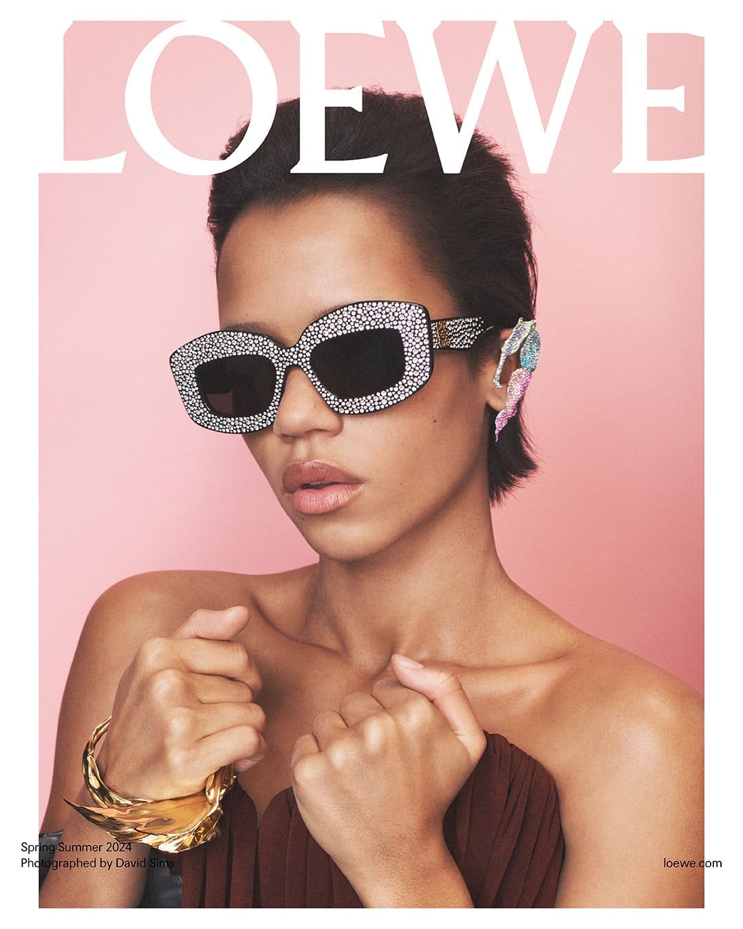 Fashion magazine cover featuring woman with crystal sunglasses, jeweled ear piece, gold bracelet, against a light pink backdrop.