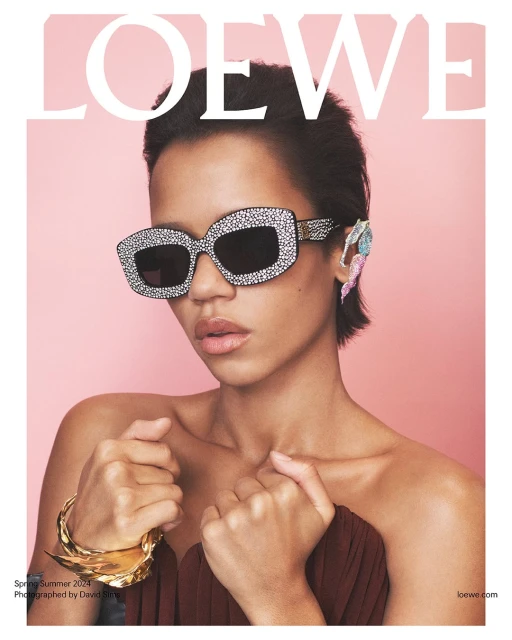 Fashion magazine cover featuring woman with crystal sunglasses, jeweled ear piece, gold bracelet, against a light pink backdrop.