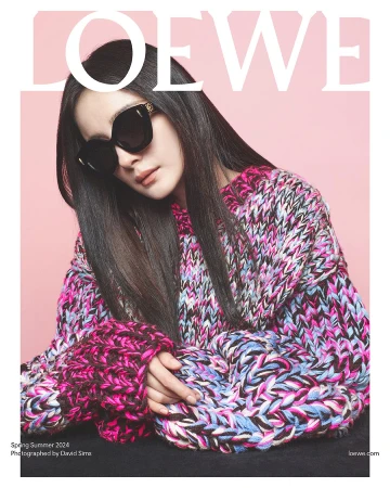 Magazine cover featuring a woman with dark hair wearing sunglasses and a colorful knit sweater against a pink background with Loewe branding.