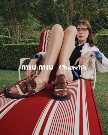 Fashion shot featuring woman on striped lounge chair, wearing glasses and Mary Jane shoes with brand logos in the foreground, trees behind.