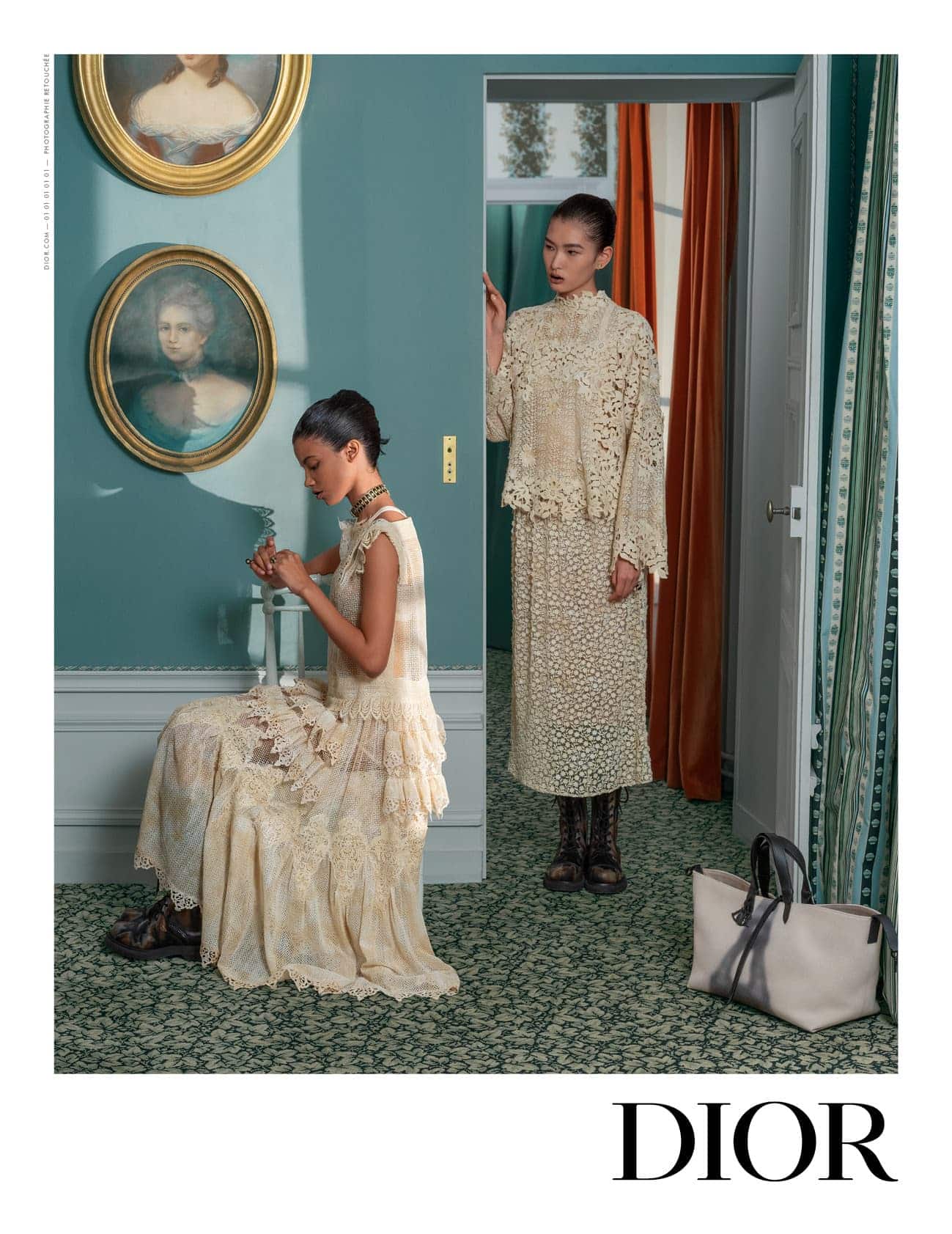 Two women in vintage-inspired dresses pose in a teal-walled room with classic paintings and carpet, next to a doorway with curtains and bag.