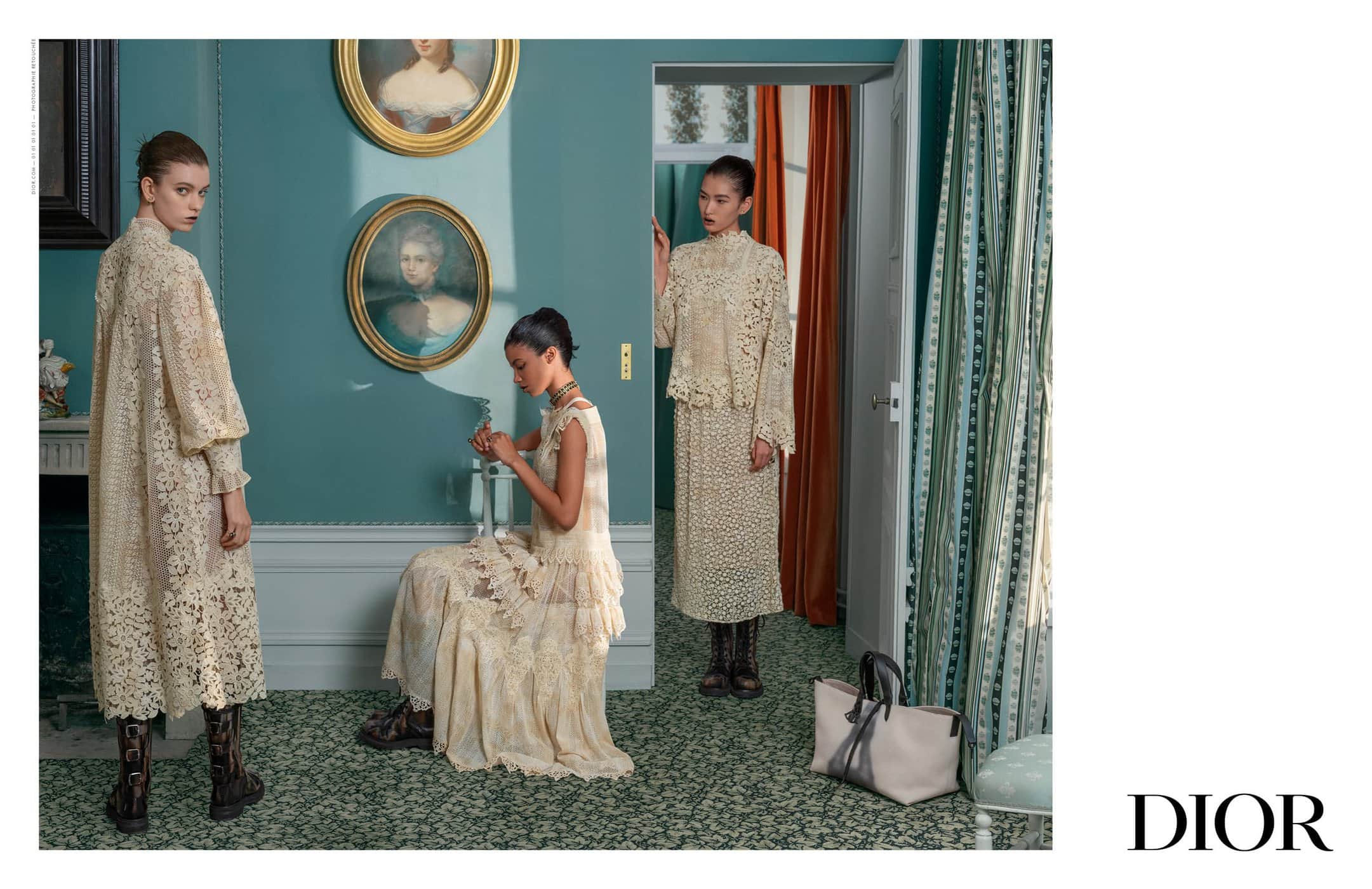 Three women model lace dresses in a vintage-style interior with portraits and a green carpet, showcasing an elegant fashion scene.