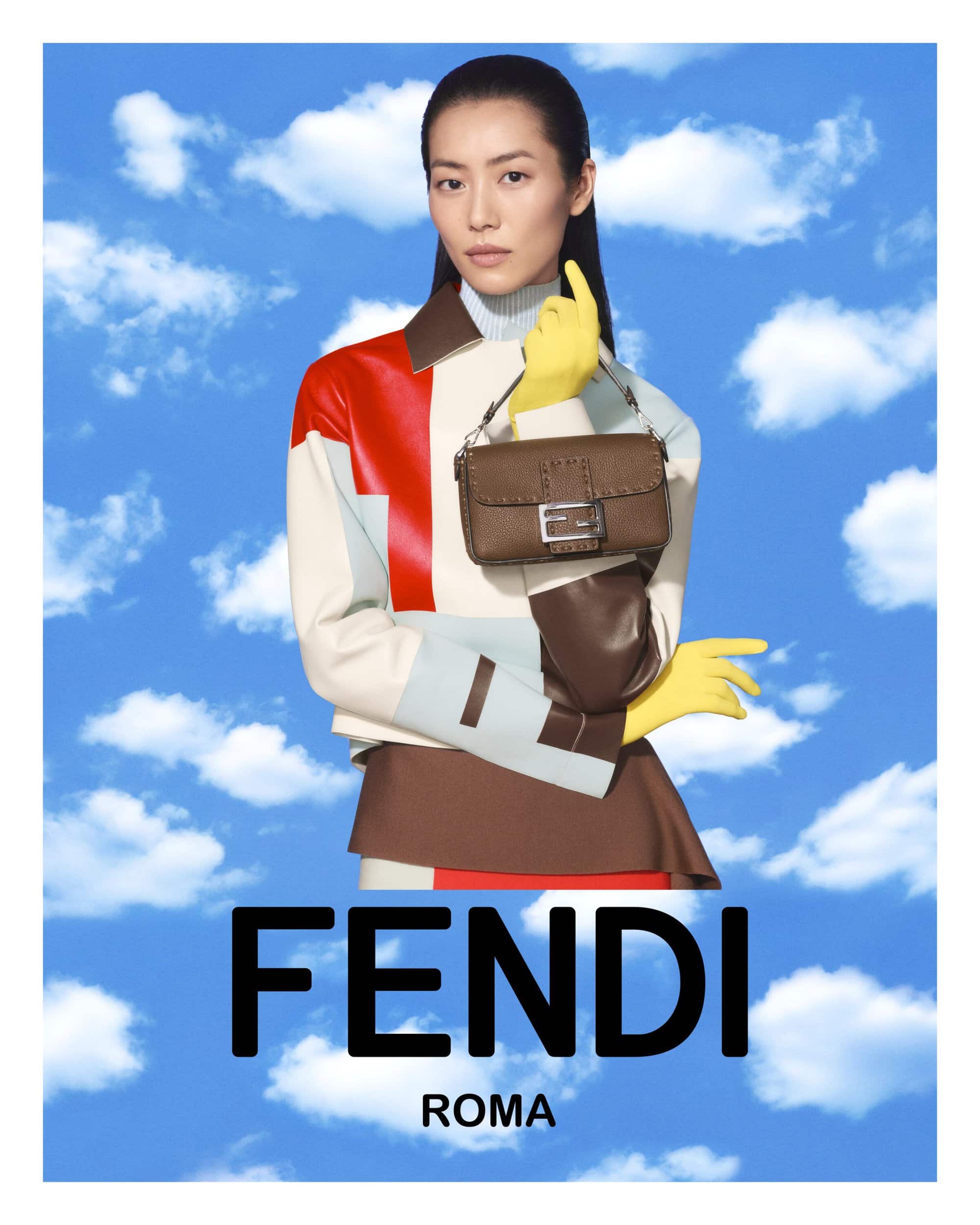 An Asian woman in a color-blocked jacket showcases a brown Fendi handbag against a blue sky with clouds in a fashion editorial.